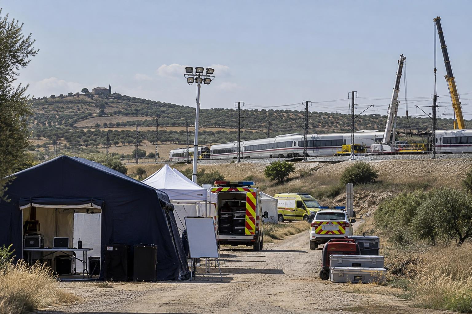 Puesto de mando avanzado junto a una vía ferroviaria en un paisaje rural de Toledo, con vehículos de emergencias, carpas de coordinación y grúas al fondo, sin personas reconocibles ni víctimas visibles.