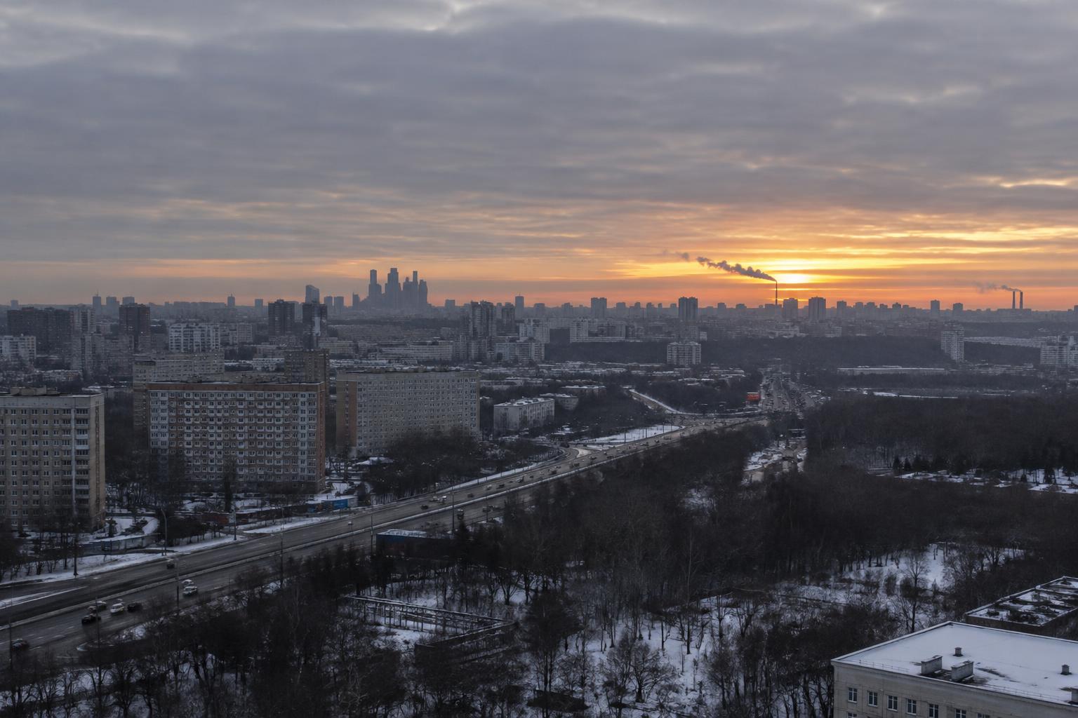 Vista panorámica realista de los alrededores de Moscú al amanecer, con bloques residenciales, una carretera y un cielo gris sobre el horizonte, sin personas reconocibles ni explosiones.