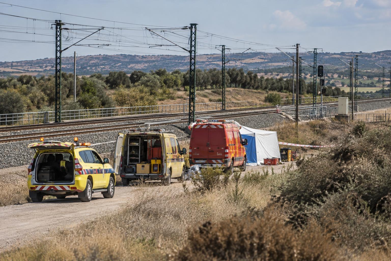 Vista exterior de una zona ferroviaria acordonada en un paisaje rural de Toledo, con vehículos de emergencias y material logístico junto a las vías, sin víctimas visibles ni personas reconocibles.